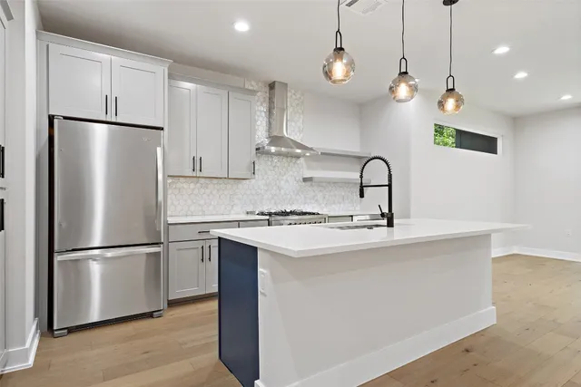 a kitchen with stainless steel appliances granite countertop a refrigerator a sink a stove a microwave and a refrigerator