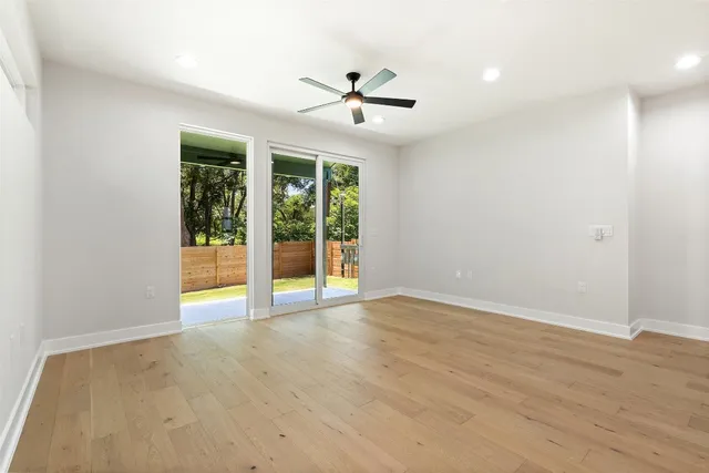 an empty room with wooden floor and a ceiling fan
