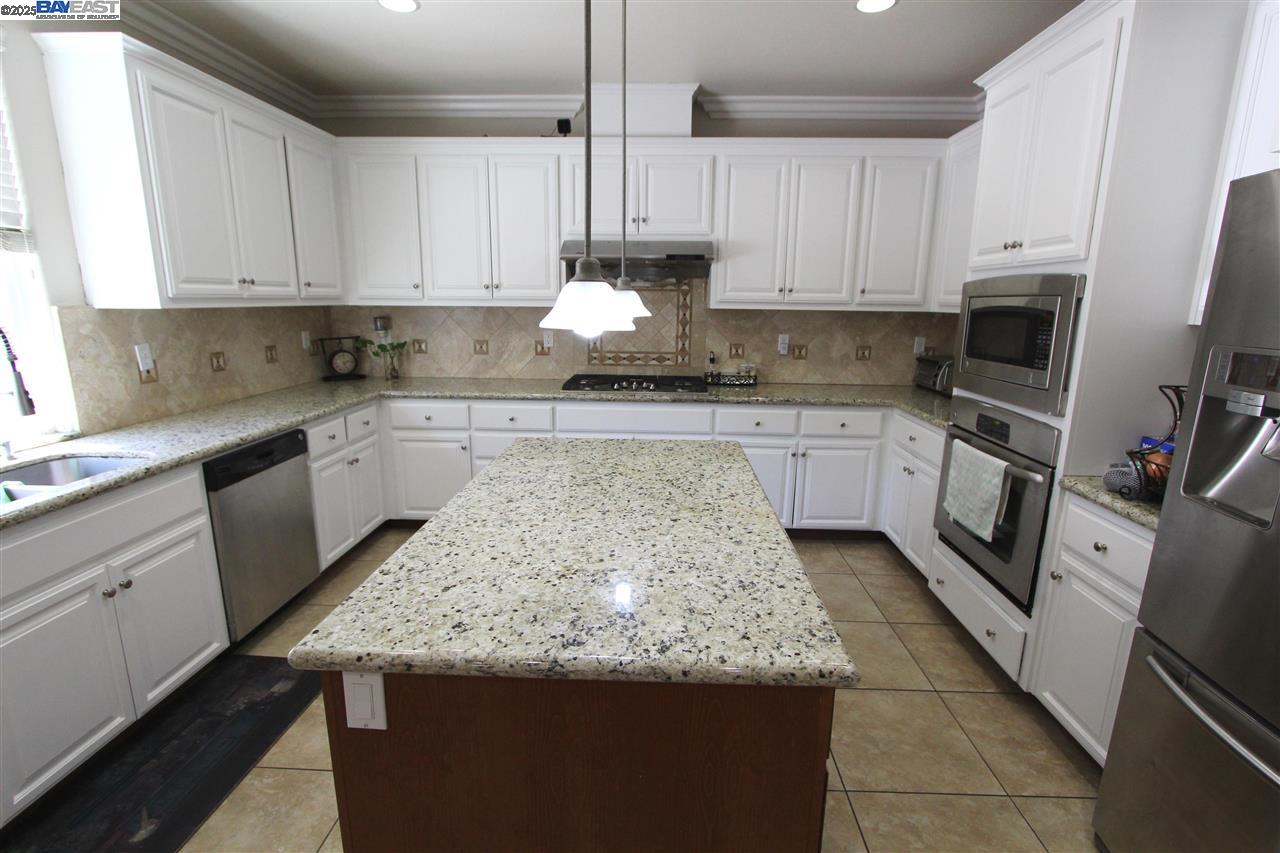 5199 Salerno Drive Dublin, CA 94568 - Photo 6 of 20 a kitchen with kitchen island granite countertop a sink counter top space appliances and cabinets
