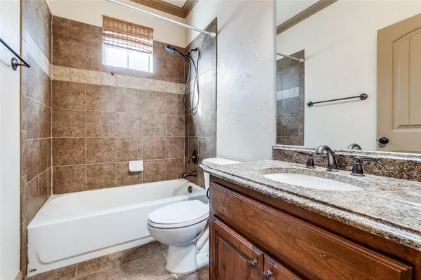 a bathroom with a granite countertop bathtub sink vanity mirror and toilet