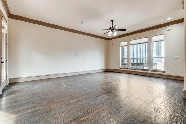 an empty room with wooden floor chandelier and windows