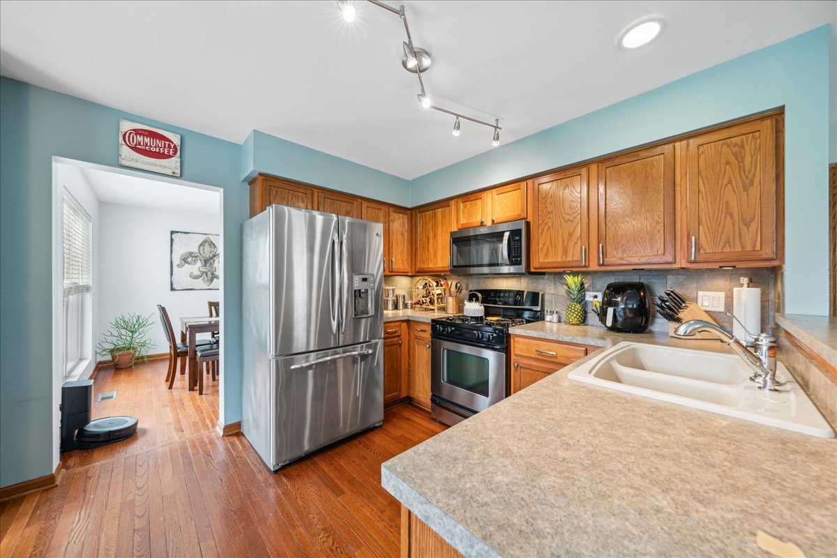 432 Butterfly Road Bolingbrook, IL 60490 - Photo 5 of 27 a kitchen with stainless steel appliances granite countertop a refrigerator a stove top oven a sink dishwasher and wooden cabinets with wooden floor