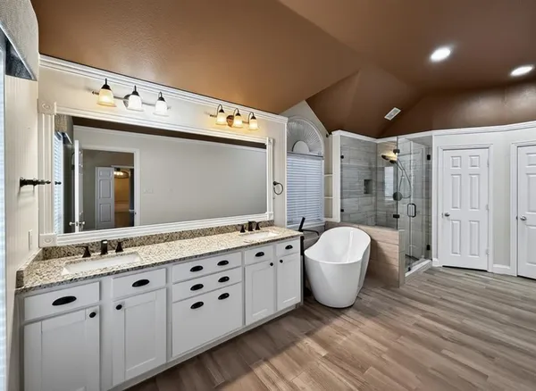 a spacious bathroom with a double vanity sink a mirror and a shower