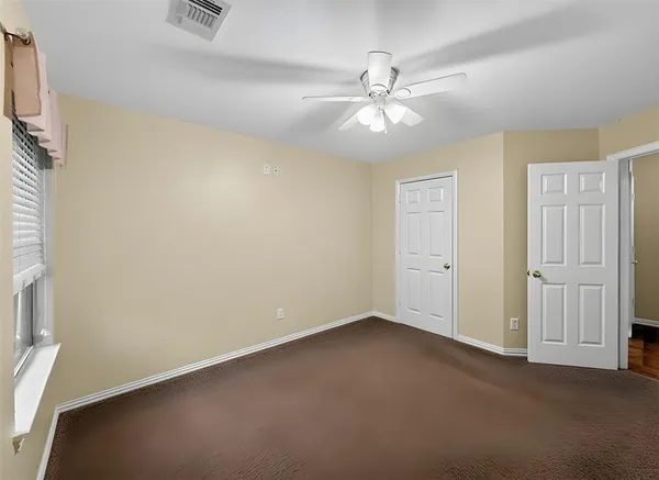 an empty room with windows and fan