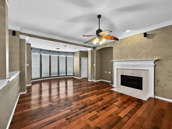a view of an empty room with wooden floor fireplace and a window