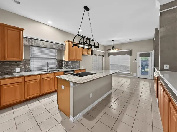 a kitchen with kitchen island granite countertop a sink a counter top space appliances and cabinets