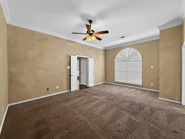 an empty room with chandelier fan and windows