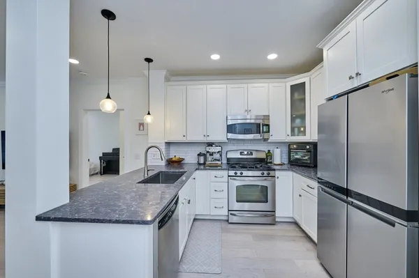 a kitchen with stainless steel appliances granite countertop a sink a stove a refrigerator and a oven