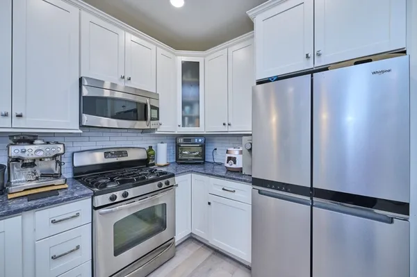 a kitchen with granite countertop cabinets stainless steel appliances and a counter space