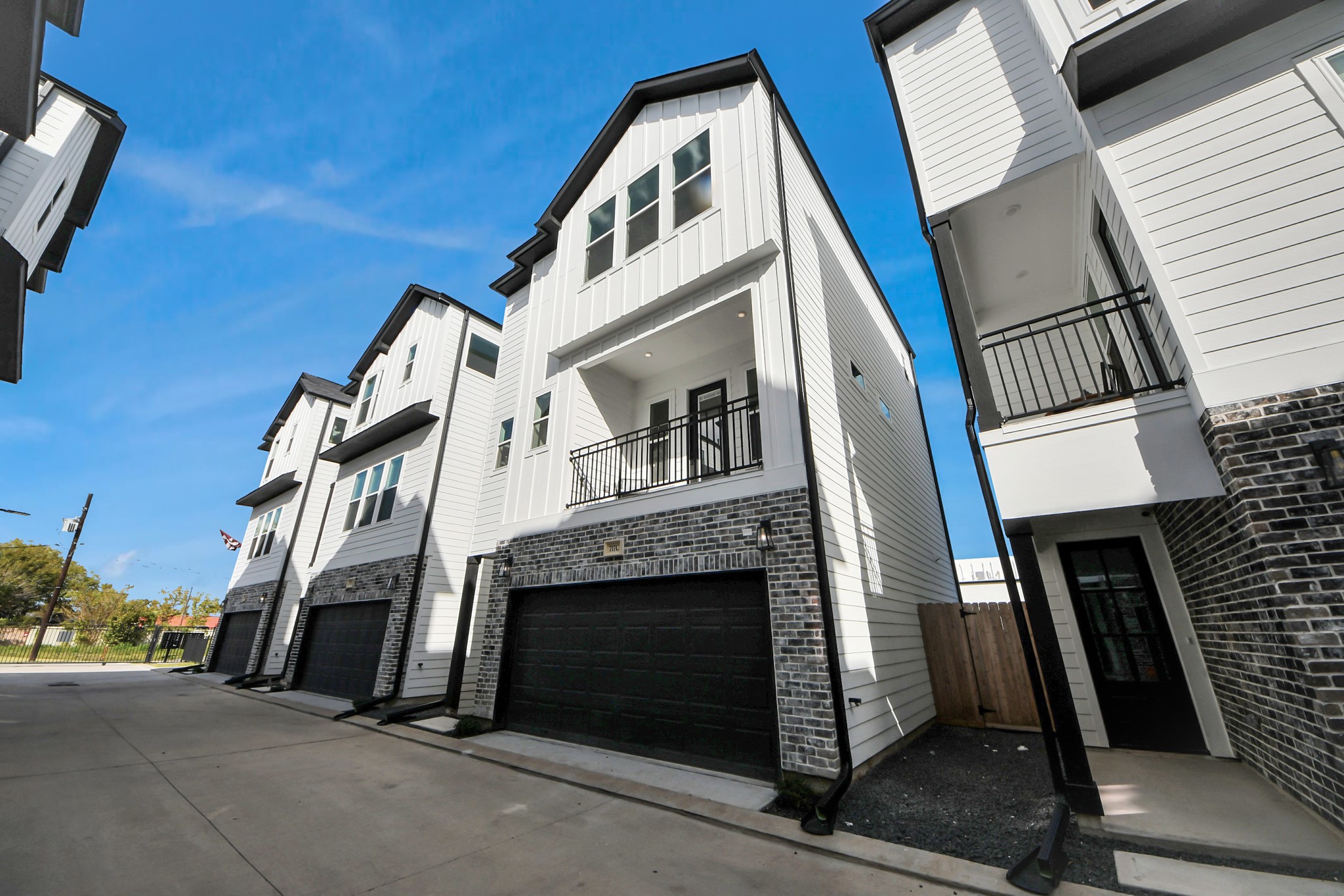723 Marcella Street, Unit A Houston, TX 77091 - Photo 3 of 24 Modern 3 level home with a sleek design, featuring a two-car garage, balcony, and large windows, captured at dusk under a vibrant sky.