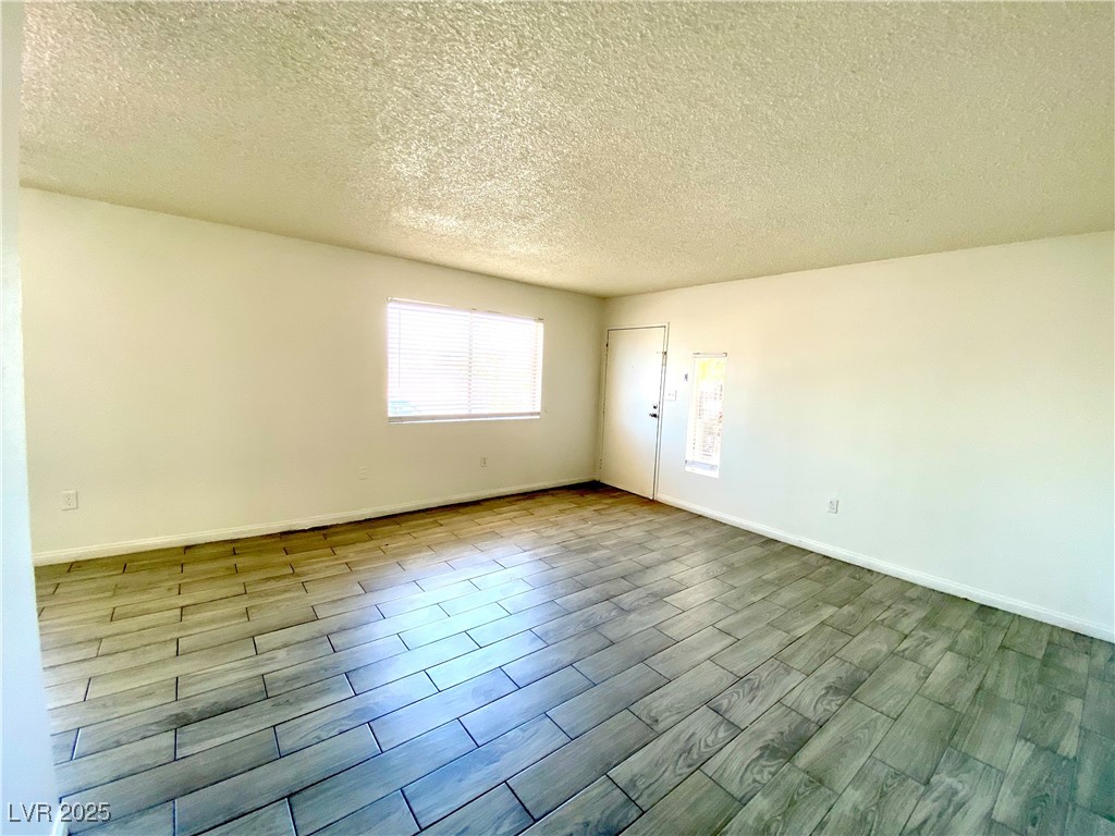 6213 Smoke Ranch Road Las Vegas, NV 89108 - Photo 17 of 22 Empty room with a textured ceiling and wood tiled floors