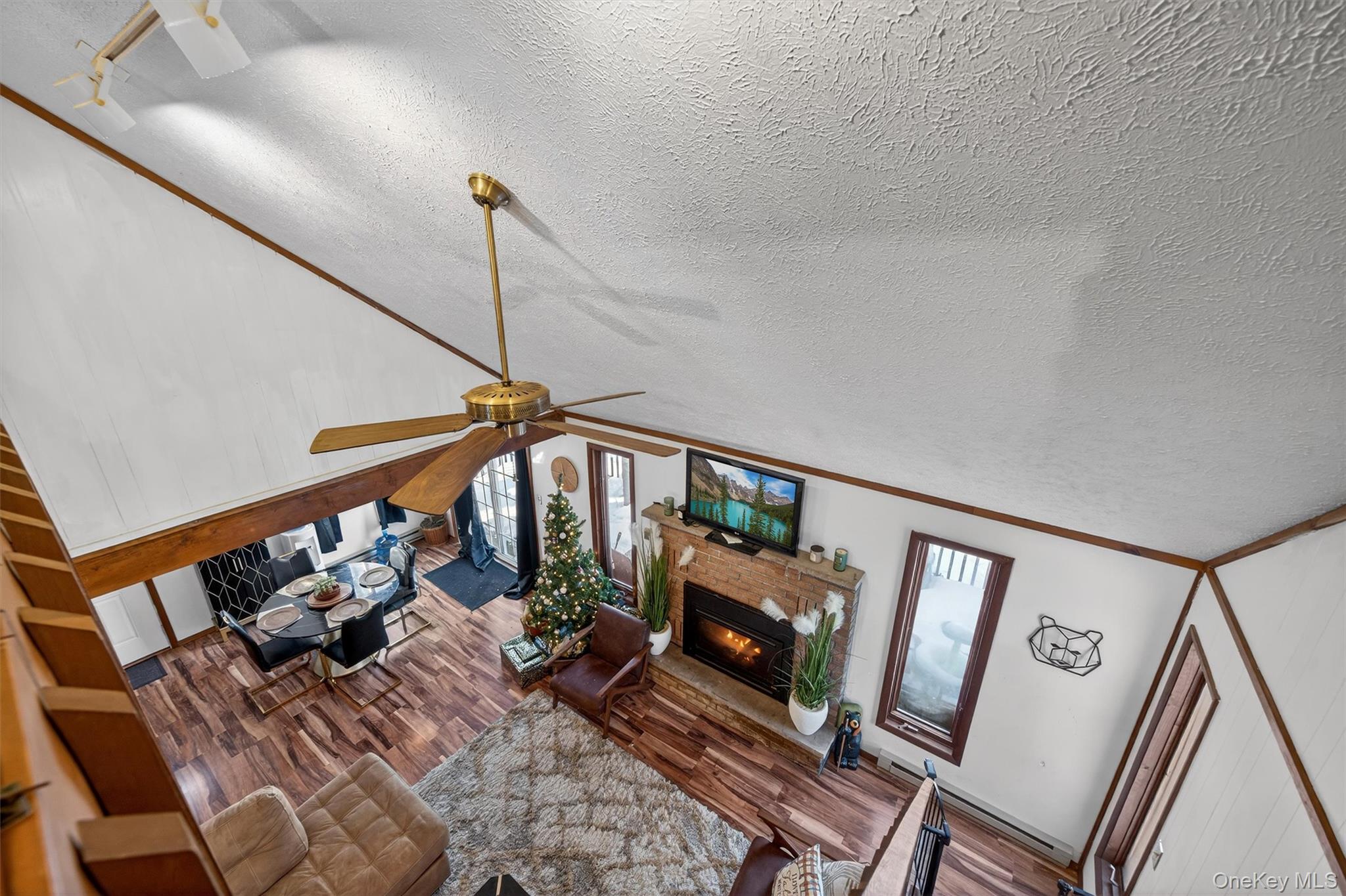 3111 Cherry Ridge Road Bushkill, PA 18324 - Photo 21 of 29 Living area featuring a textured ceiling, a glass covered fireplace, ceiling fan, ornamental molding, and wood finished floors