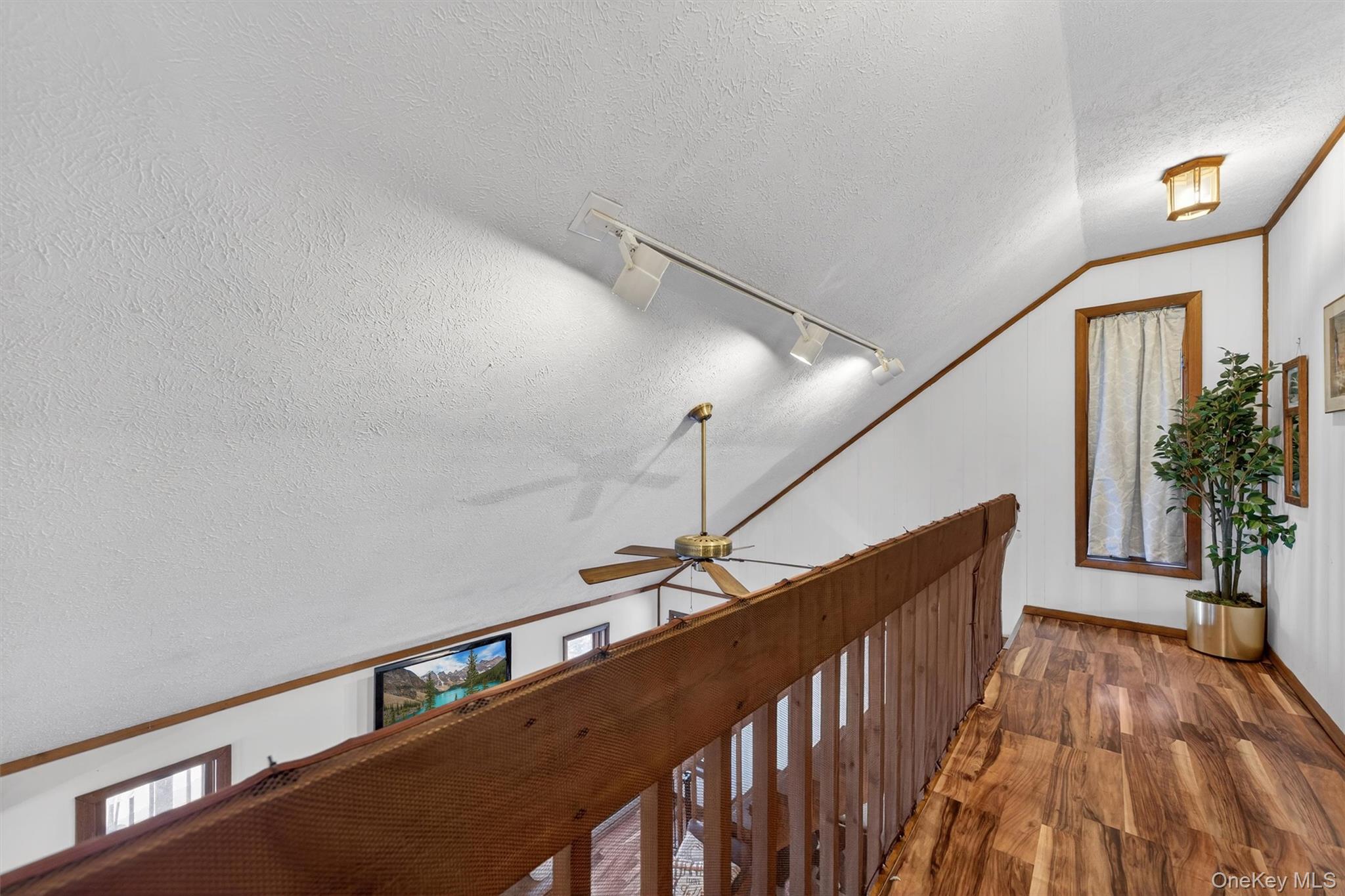 3111 Cherry Ridge Road Bushkill, PA 18324 - Photo 22 of 29 Corridor with lofted ceiling, a textured ceiling, wood finished floors, and track lighting