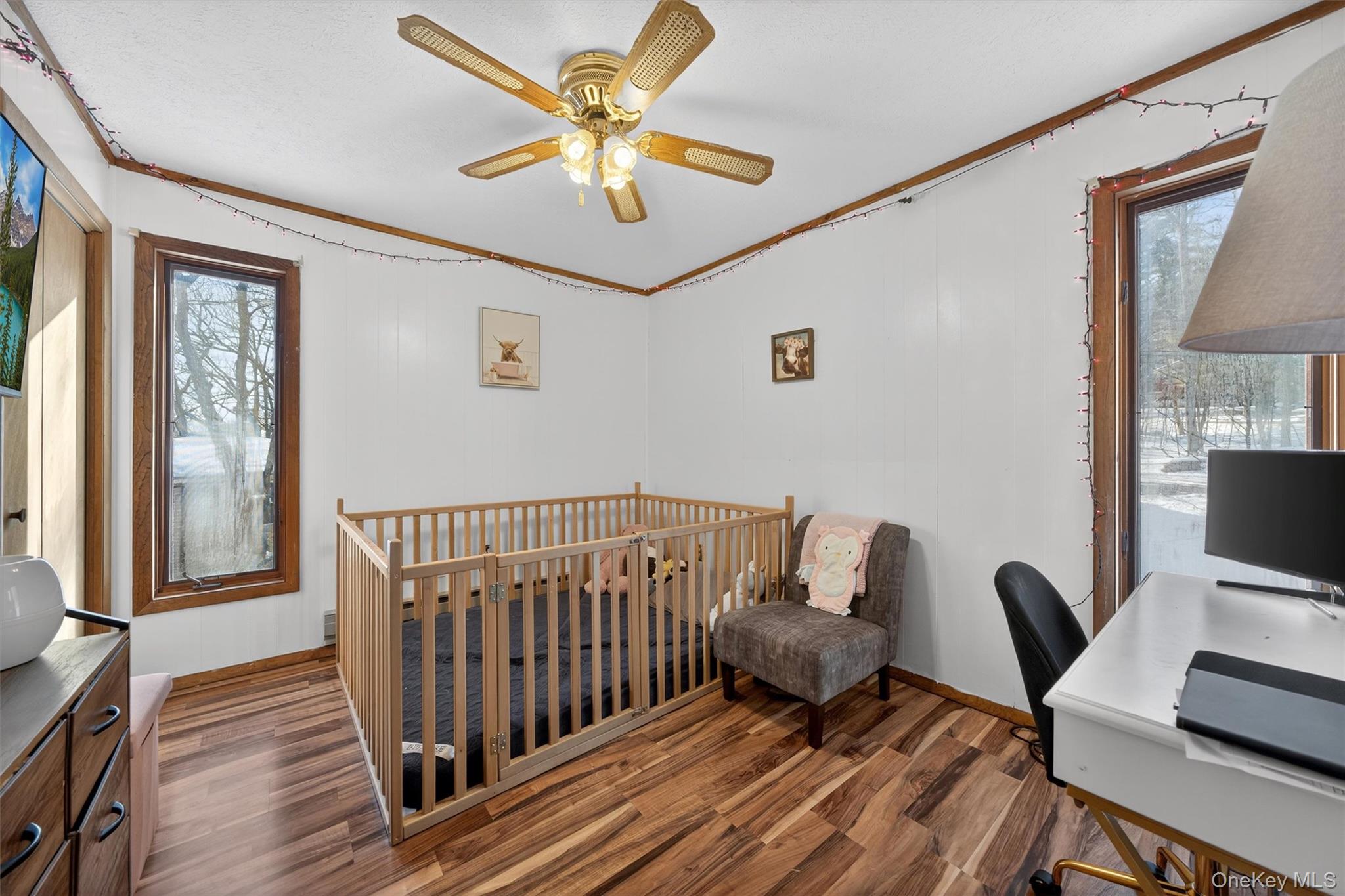 3111 Cherry Ridge Road Bushkill, PA 18324 - Photo 25 of 29 Bedroom featuring a crib, ornamental molding, wood finished floors, a ceiling fan, and an office area