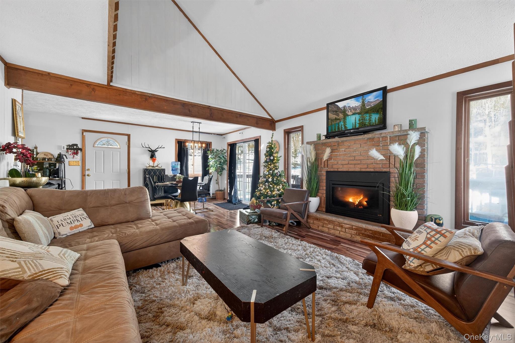 3111 Cherry Ridge Road Bushkill, PA 18324 - Photo 8 of 29 Living room featuring a fireplace, wood finished floors, high vaulted ceiling, a chandelier, and crown molding