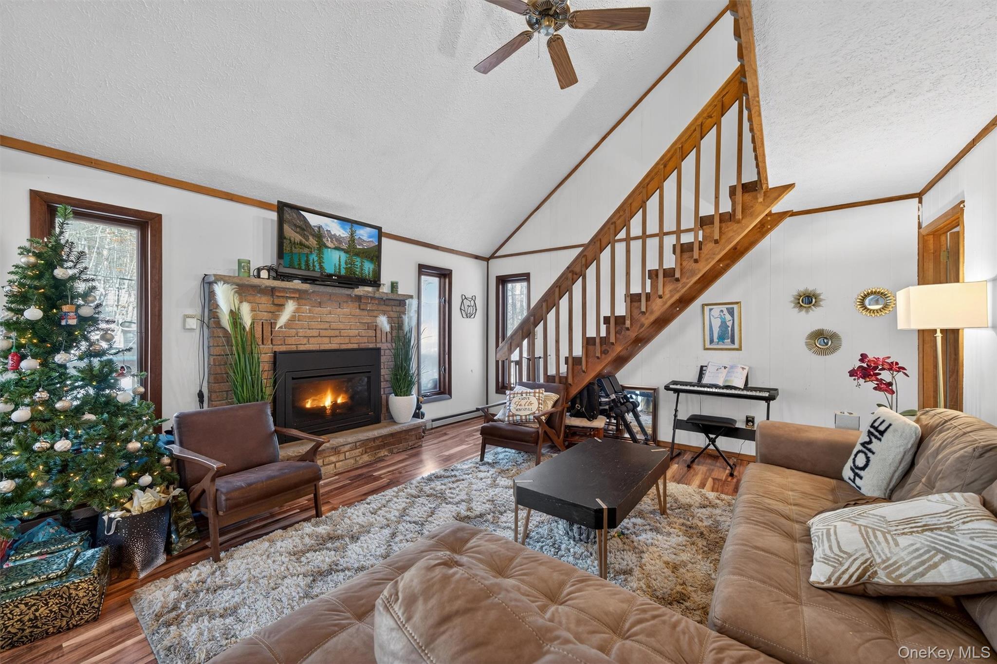 3111 Cherry Ridge Road Bushkill, PA 18324 - Photo 10 of 29 Living room with a textured ceiling, wood finished floors, ornamental molding, a brick fireplace, and a baseboard heating unit