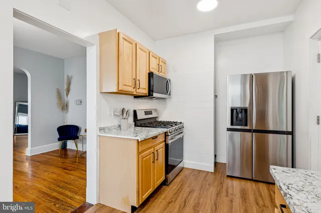 a kitchen with a refrigerator stove and wooden floor