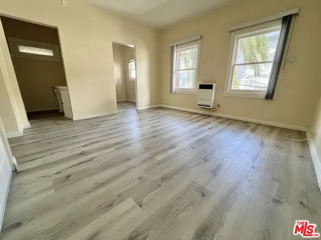 a view of empty room with window and wooden floor
