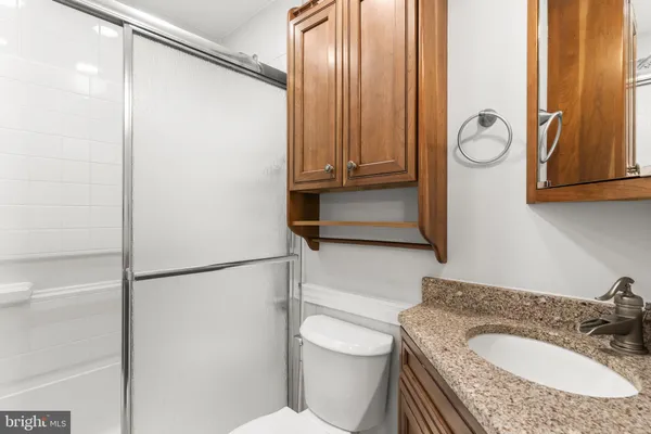 a bathroom with a granite countertop sink mirror vanity and toilet