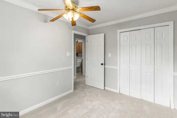 an empty room with closet and a chandelier fan