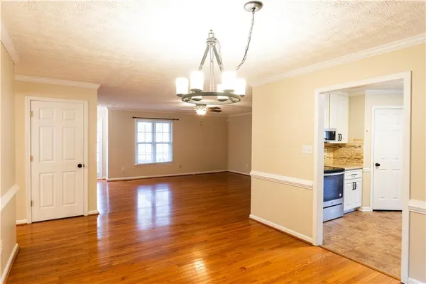 a view of a hallway with wooden floor and chandelier