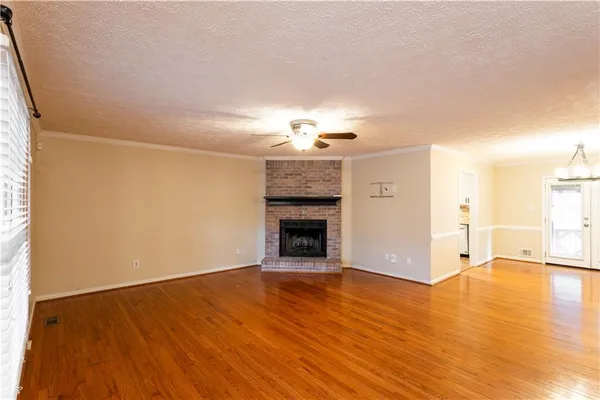 a view of an empty room with wooden floor and a fireplace