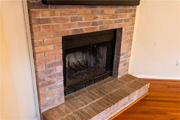 an empty room with wooden floor fireplace and windows