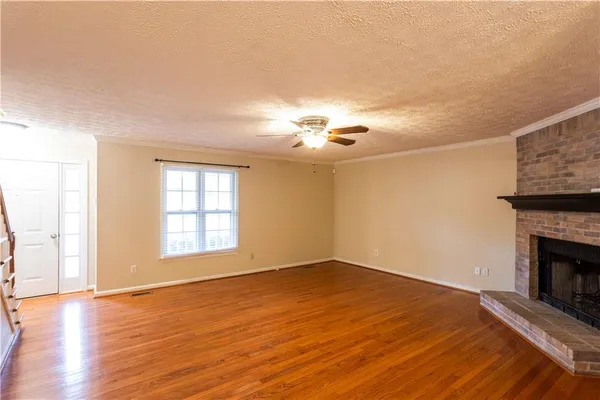 a view of an empty room with window and wooden floor