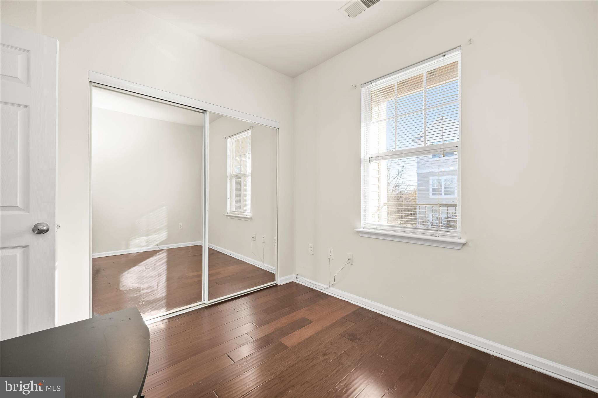 19620 Galway Bay Circle, Unit 302 Germantown, MD 20874 - Photo 30 of 36 an empty room with wooden floor and windows
