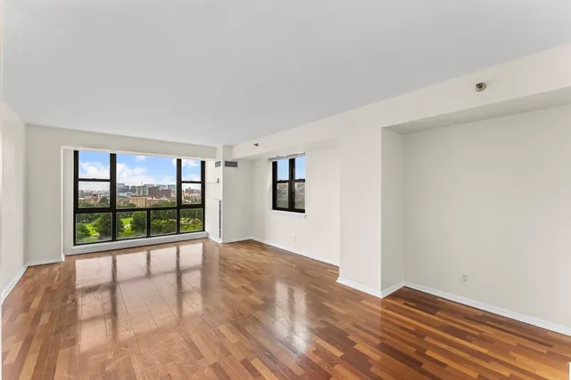 a view of an empty room with wooden floor and a window