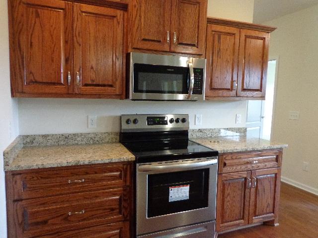 1455 Cliff Amos Road Spring Hill, TN 37174 - Photo 5 of 24 a kitchen with granite countertop wood cabinets and stainless steel appliances