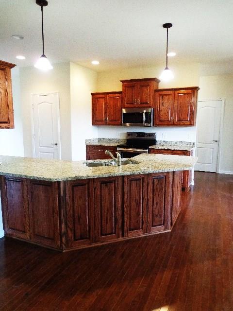 1455 Cliff Amos Road Spring Hill, TN 37174 - Photo 6 of 24 a kitchen with stainless steel appliances granite countertop wooden floors wooden cabinets a refrigerator and a sink