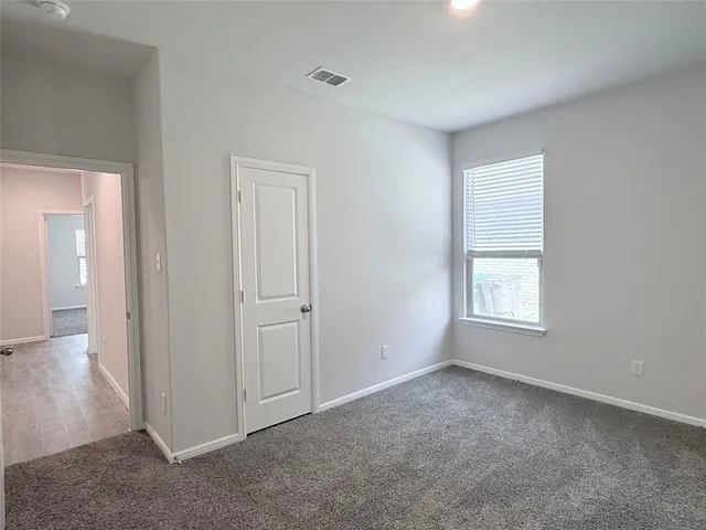 a view of an empty room with closet and a window