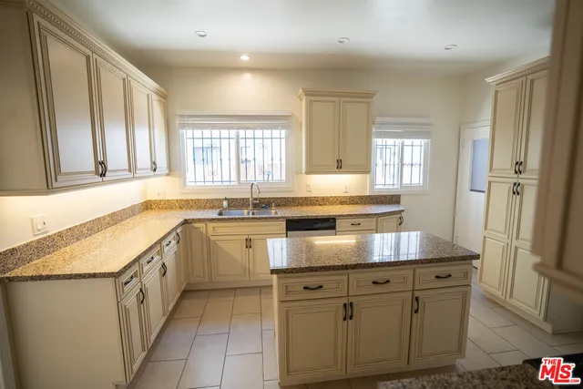 a kitchen with granite countertop white cabinets white stainless steel appliances a sink and a window