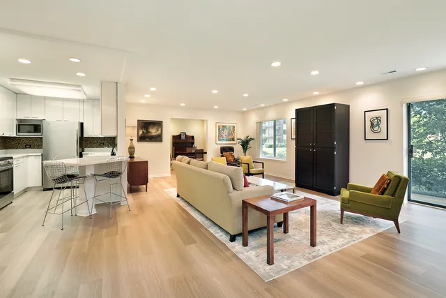 a living room with furniture kitchen view and a wooden floor