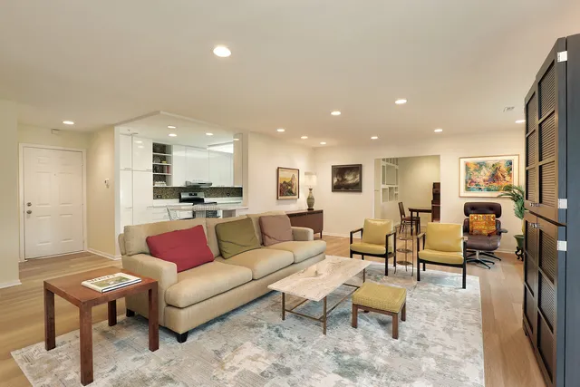 a living room with furniture a dining table wooden floor and a kitchen view
