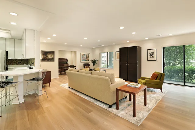 a kitchen with stainless steel appliances kitchen island granite countertop a refrigerator a stove a sink dishwasher and white cabinets with wooden floor