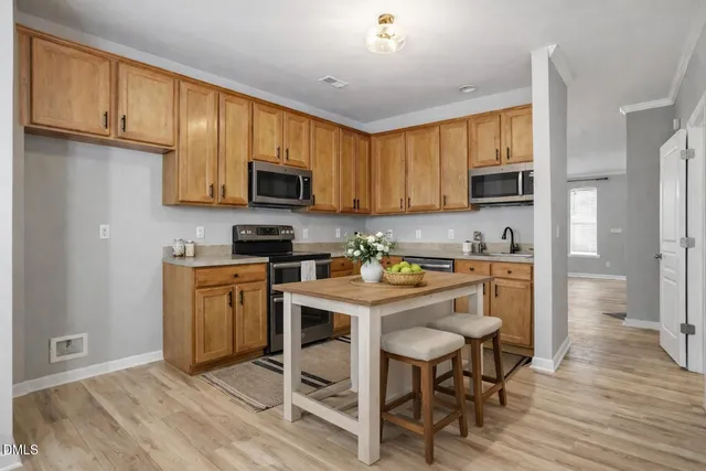 a kitchen with stainless steel appliances granite countertop wooden cabinets a stove a sink and a refrigerator