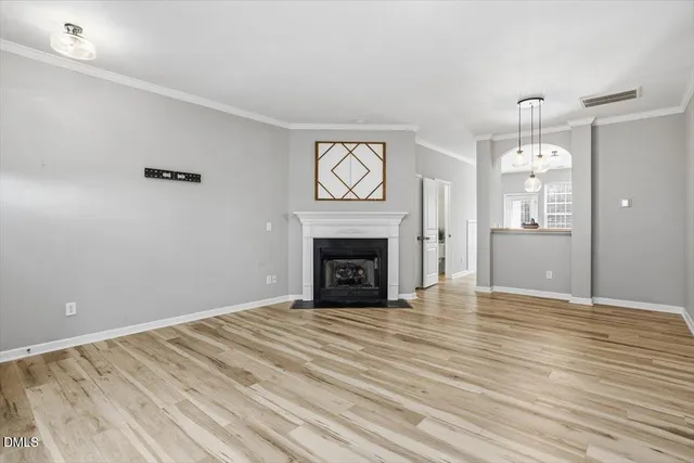 a view of an empty room with wooden floor fireplace and a window