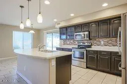 a kitchen with kitchen island granite countertop stainless steel appliances a sink a stove a counter space and cabinets