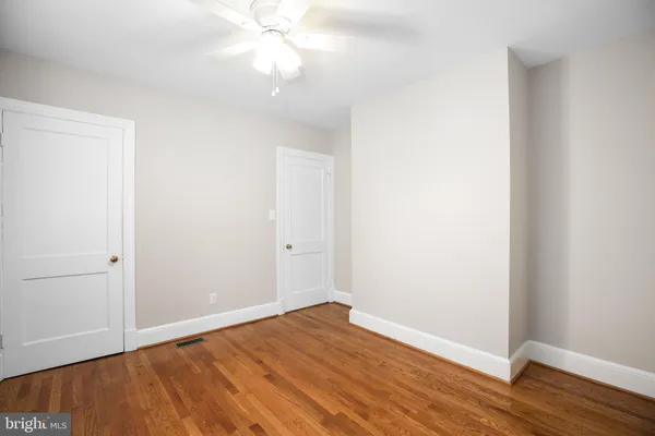 an empty room with wooden floor and fan