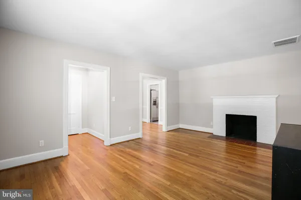 a view of an empty room with wooden floor fireplace and a window