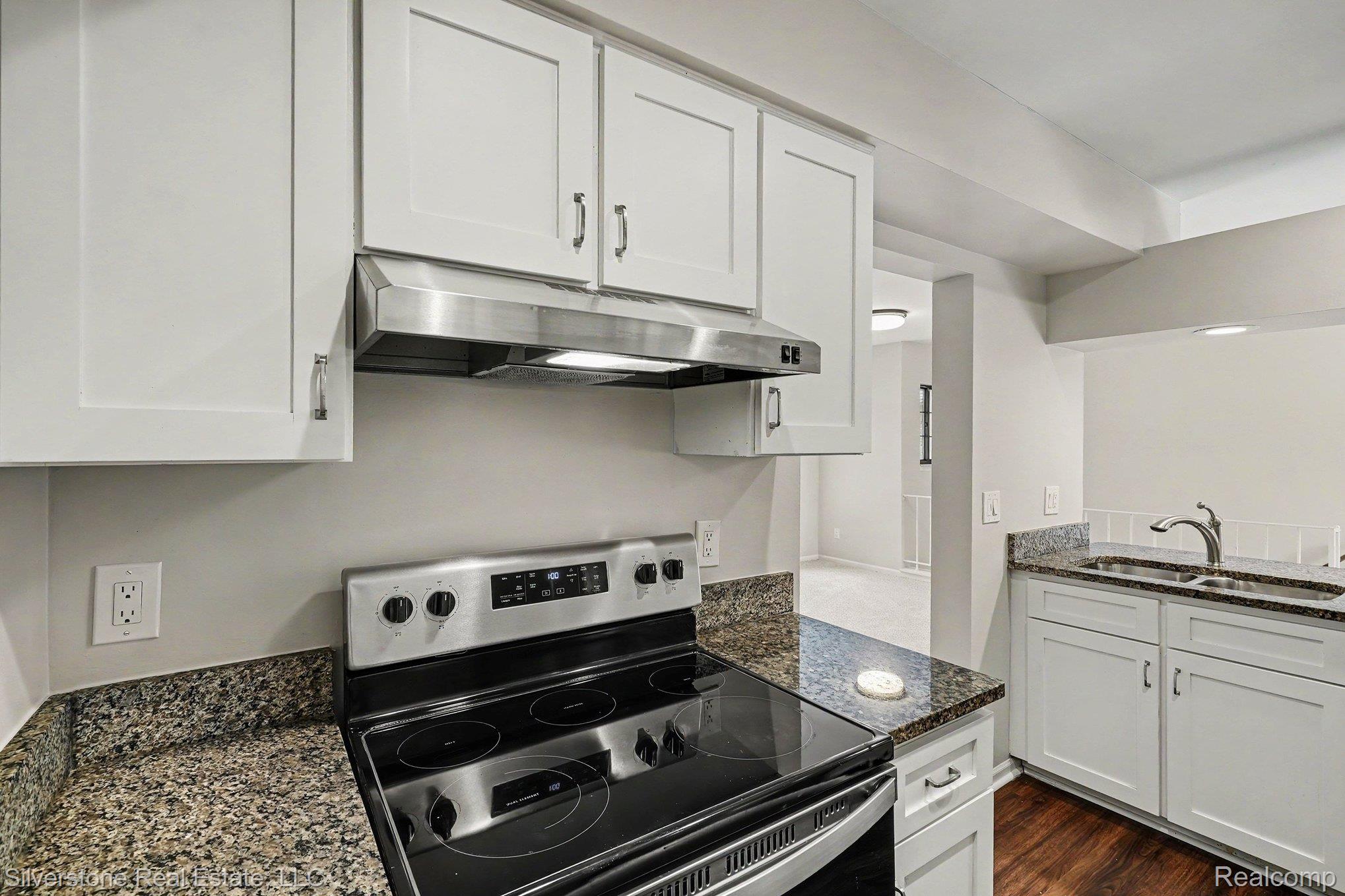 1502 Meadowside Drive Rochester, MI 48307 - Photo 11 of 27 Modern kitchen featuring white shaker cabinetry, stainless steel appliances, granite-style countertops, and wood-finish flooring