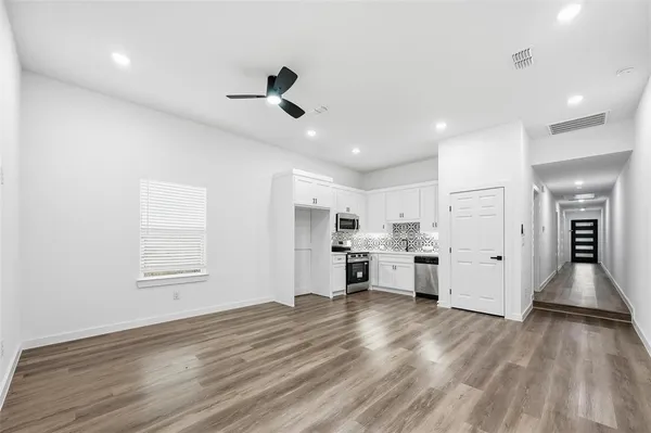 a view of a kitchen with center island wooden floor stainless steel appliances and cabinets