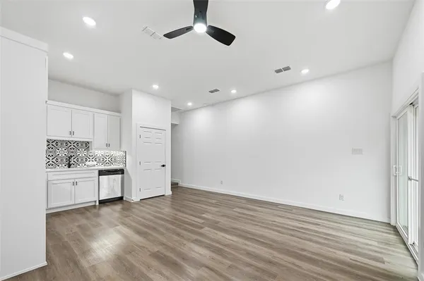 an empty room with wooden floor cabinet and windows