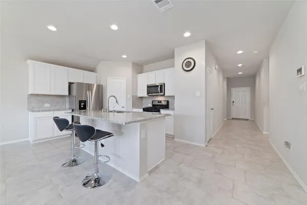 a kitchen with kitchen island granite countertop appliances cabinets and a sink