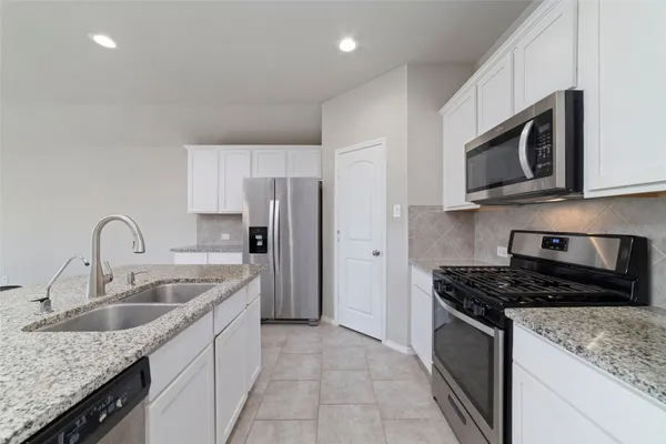 a kitchen with stainless steel appliances granite countertop a sink stove microwave and refrigerator