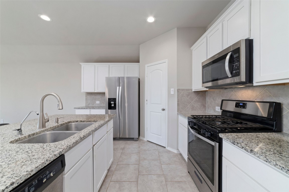 24323 Winchelsea Lane Spring, TX 77389 - Photo 16 of 27 a kitchen with stainless steel appliances granite countertop a sink stove microwave and refrigerator