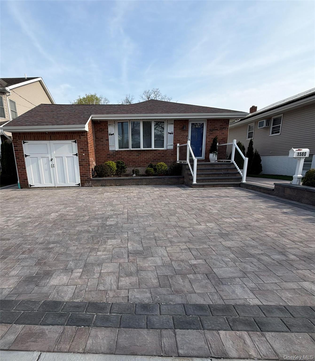 The property features a brick exterior, a two-door garage, and a paved driveway