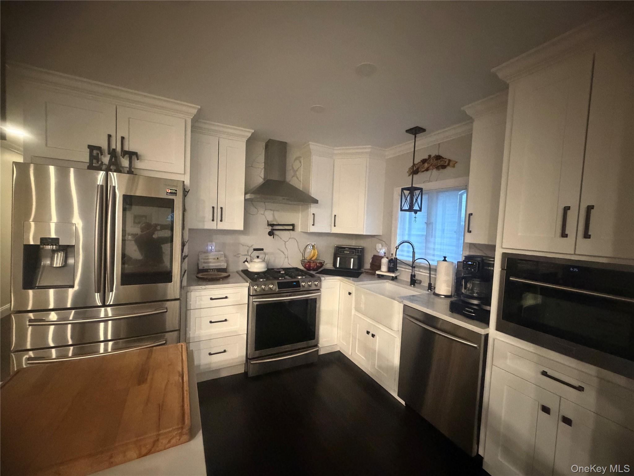 1580 North Jerusalem Road Merrick, NY 11566 - Photo 12 of 36 This kitchen features white cabinetry with dark hardware, dark flooring, and stainless steel appliances including a refrigerator, range, and dishwasher